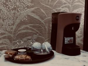 uma máquina de café e chávenas numa bandeja ao lado de uma mesa em La Meridiana d'Alba em Alba