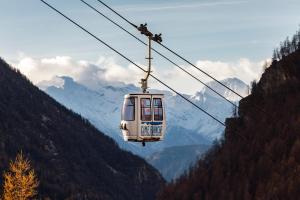 un teleférico está volando por las montañas en HelloChalet - Le Fleury Family Apartment 600mt cablecar, en Valtournenche