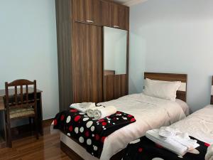 1 dormitorio con 2 camas, silla y espejo en Guest House Gaenati, en Kutaisi