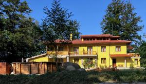 ein großes gelbes Haus mit einem Balkon und Bäumen in der Unterkunft Вила Ренесанс Костенец in Kostenez