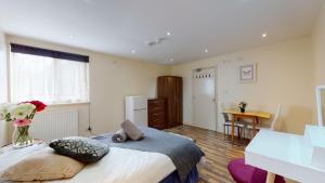 a bedroom with a bed with a vase of flowers on it at 247London Studio Flats in London