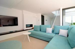 ein Wohnzimmer mit einer blauen Couch und einem Fernseher in der Unterkunft VILLA PINELL in Torroella de Montgrí