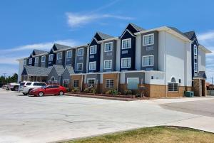 un gran edificio con coches estacionados en un estacionamiento en Microtel Inn & Suites by Wyndham Oklahoma City Airport en Bethany