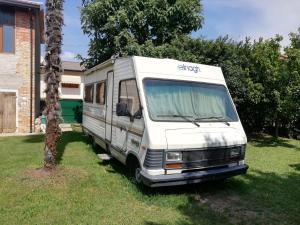 Una furgoneta blanca estacionada en el césped junto a una casa en Il Camper di Ermione en Cordenons