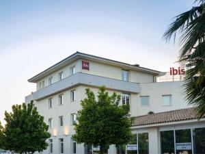 a large white building with a red sign on it at Ibis Sevilla in Seville