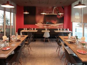 een restaurant met houten tafels en stoelen en rode muren bij Ibis Sevilla in Sevilla