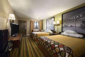 a hotel room with two beds and a flat screen tv at Super 8 by Wyndham Childress in Childress