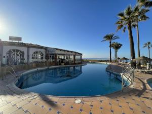 duży basen obok plaży z palmami w obiekcie Dona Lola Micaela Beach front duplex apartment with open sea and beach views located between Marbella and Fuengirola - Costa del Sol - CS148 w mieście Mijas