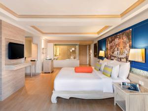 Novotel Phuket Resort في شاطيء باتونغ: غرفه فندقيه سرير كبير وتلفزيون