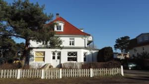ein weißes Haus mit rotem Dach hinter einem weißen Zaun in der Unterkunft Haus Sonneneck 2 in Dierhagen