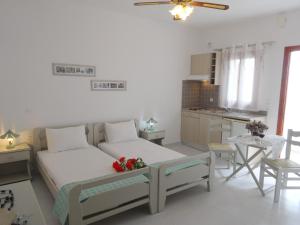 a white bedroom with a bed and a kitchen at Kamakaris Rooms in Adamantas