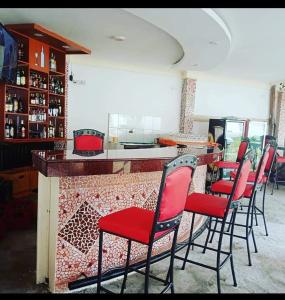 a bar with red chairs and a counter in a restaurant at Platinum Hotels Mombasa in Shanzu
