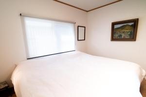 ein Schlafzimmer mit einem weißen Bett und einem Fenster in der Unterkunft Immaculate Private Family Cottage with Hot Spring in Towada