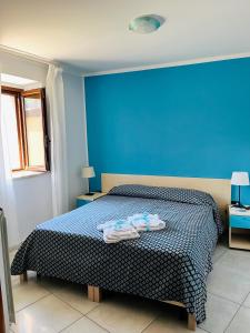 - une chambre bleue avec un lit et des serviettes dans l'établissement La Casa al Piccolo Borgo, à Vallo della Lucania