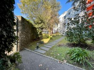 a garden with a brick wall next to a sidewalk at Appartement cosy jardin des plantes avec parking in Nantes