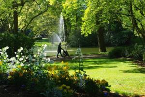 Una mujer caminando por un parque con una fuente en Appartement cosy jardin des plantes avec parking, en Nantes