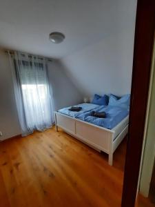 Schlafzimmer mit einem Bett mit blauer Bettwäsche und einem Fenster in der Unterkunft Casa Luna in Donnerskirchen