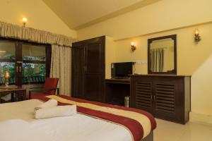 a bedroom with two beds and a desk and a mirror at Wintergreen Water Front Resort in Tripunnittara