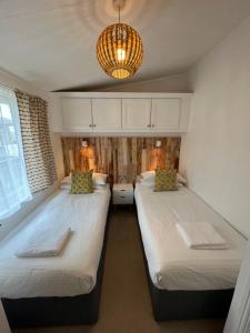 two beds in a small room with a chandelier at Cornish Beach Lodge in Torpoint