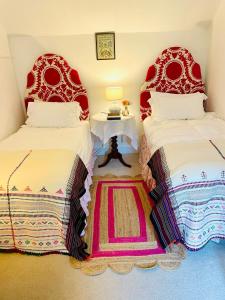 een slaapkamer met 2 bedden met rode hoofdeinden en een tafel bij Storm Cottage in Langham