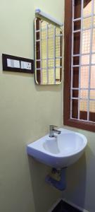 ein Badezimmer mit einem weißen Waschbecken und einem Spiegel in der Unterkunft Sivakumar Paradise in Mahabalipuram