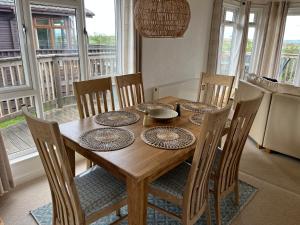 stół jadalny z krzesłami oraz drewniany stół z płytami w obiekcie Cornish Beach Lodge w mieście Torpoint