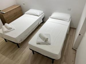 two beds in a room with white sheets and towels at Villa Milano Apt. n. 1 in Milan