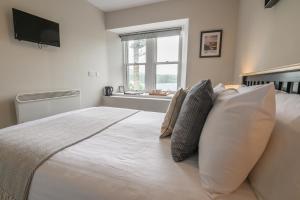 a bedroom with a large white bed with pillows and a window at Coolin View in Portree