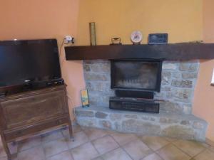 a living room with a stone fireplace with a flat screen tv at Maison de vacances en Ardèche in Pailharès