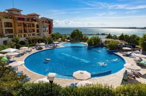 a large swimming pool with chairs and umbrellas at Sea View Holiday for Family and Friends Aheloy, near Sunny Beach-Почивка с изглед към морето за семейство и приятели Ахелой, близо до Слънчев бряг in Aheloy