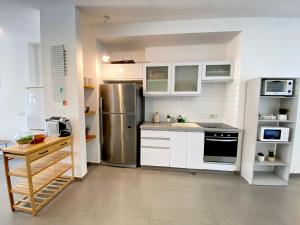 una cucina con armadi bianchi e frigorifero in acciaio inossidabile di The Grand Hertzel a Tel Aviv