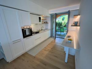a kitchen with white cabinets and a table in it at Verbano Boutique Apartment in Meina