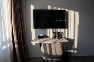 a room with a table with a television on a wall at Hotel Hvide Falk in Ilulissat +14 photos