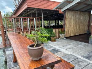 een houten tafel met een potplant op een patio bij Lanta Sabai Day House in Koh Lanta