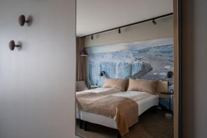 a bedroom with a bed with a painting on the wall at Hotel Hvide Falk in Ilulissat