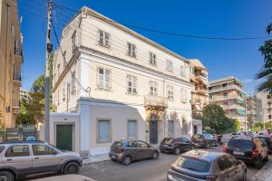 a large white building with cars parked on a street at Modern-Vintage Old Town Suites in Corfu