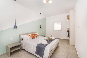 Dormitorio blanco con cama y mesa en Coste Ponente Appartamenti Turistici, en Ragusa