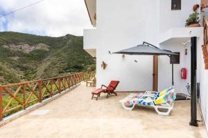 a patio with two chairs and an umbrella on a balcony at Casa en Anaga Senderismo naturaleza y desconexión in Santa Cruz de Tenerife
