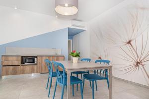 ein Esszimmer mit einem Tisch und blauen Stühlen in der Unterkunft Coste Ponente Appartamenti Turistici in Ragusa