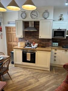 a kitchen with white cabinets and clocks on the wall at The Corner House Belford in Belford