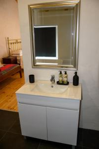 La salle de bains est pourvue d'un lavabo blanc et d'un miroir. dans l'établissement Casa das Pedras Country Retreat, à Santo António das Areias