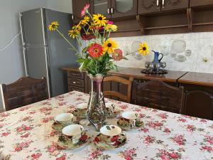 un jarrón de flores en una mesa con platos y tazas en Guest House Gaenati, en Kutaisi