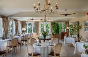 un comedor con mesas y sillas y una lámpara de araña en Logis Le Fleuray, en Cangey