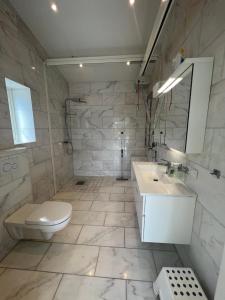 a white bathroom with a toilet and a sink at Luxory Vättern Lake Villa in Motala