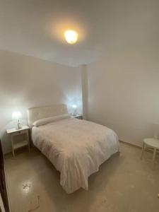 a white bedroom with a bed and two tables at Banda playa 82, en pleno corazón de Sanlucar in Sanlúcar de Barrameda