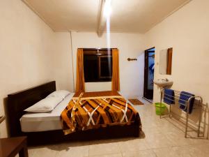 a bedroom with a bed and a window and a toilet at Peno Homestay in Sumberbuluh