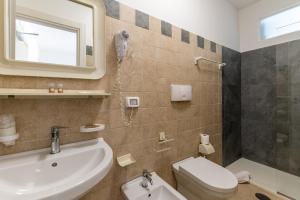 a bathroom with a sink and a toilet and a mirror at Calanca Apulian Residence in Torre Santa Sabina