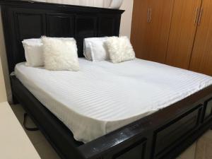 ein Bett mit weißer Bettwäsche und Kissen darauf in der Unterkunft PASWELL'S HOMES 3 Bedroom Apartment at Greatwall Gardens in Athi River