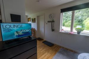 a living room with a flat screen tv on a dresser at Norra Häljaröd in Farhult