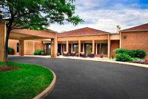 a large brick building with chairs in a driveway at Courtyard By Marriott Hartford Windsor Airport in Windsor